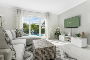 A modern living room with a sofa, coffee table, and TV. - RiversideSun: Pompano Beach Retreat, mins to beach (Pompano Beach)