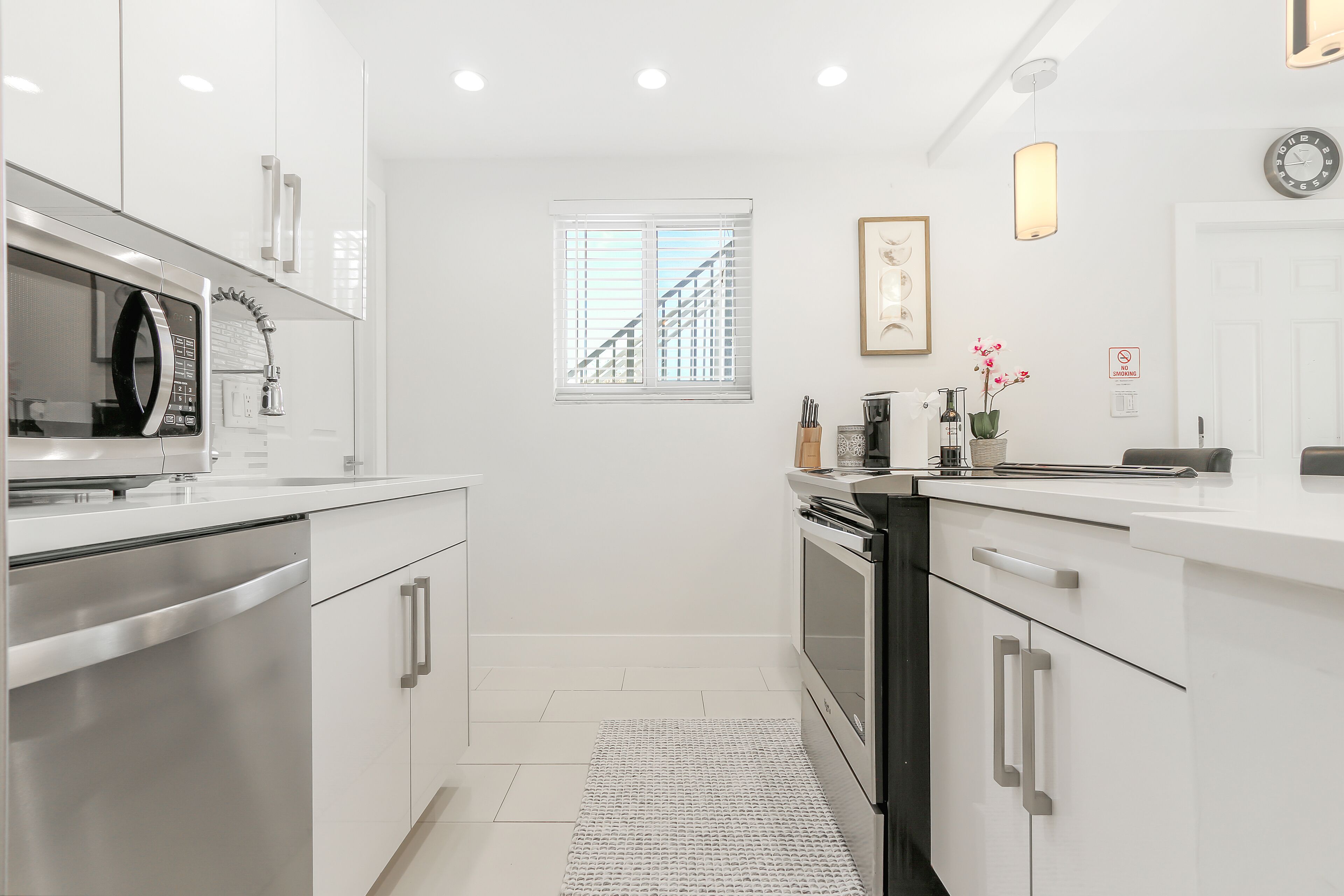 A modern kitchen with stainless steel appliances, a window with blinds, and a kitchen island.