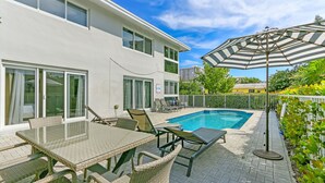 A modern house with a swimming pool, outdoor furniture, and a covered patio area.