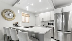 A modern kitchen with a central island, stainless steel appliances, and white cabinetry.