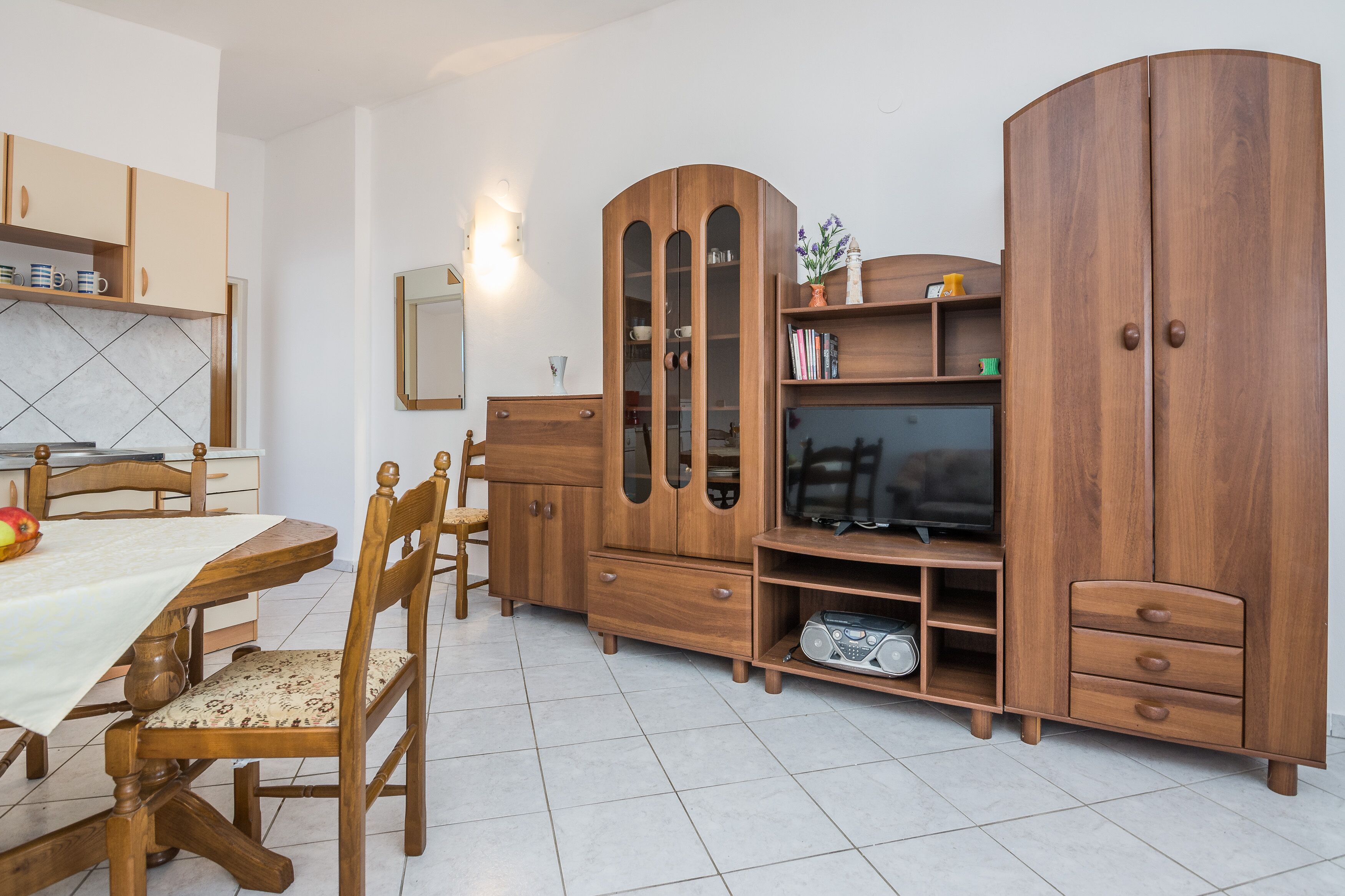 Un espace de vie compact comprenant une table à manger, des chaises, un meuble en bois avec un téléviseur et un miroir.