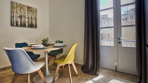 A dining area with a table set for two, featuring modern chairs and a painting on the wall. - Ursula Suites- Self Catering Apartments- Valletta- by Tritoni Hotels (Valletta)