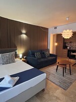 Una habitación de hotel moderna con una cama grande, un sofá, una mesa de comedor y una zona de cocina.