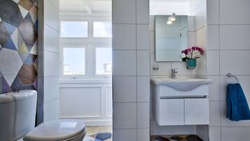 A modern bathroom with a toilet, sink, and mirror.