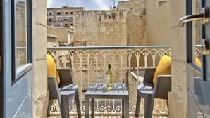 A balcony with two chairs and a table, featuring a view of the cityscape. - Ursula Suites- Self Catering Apartments- Valletta- by Tritoni Hotels (Valletta)