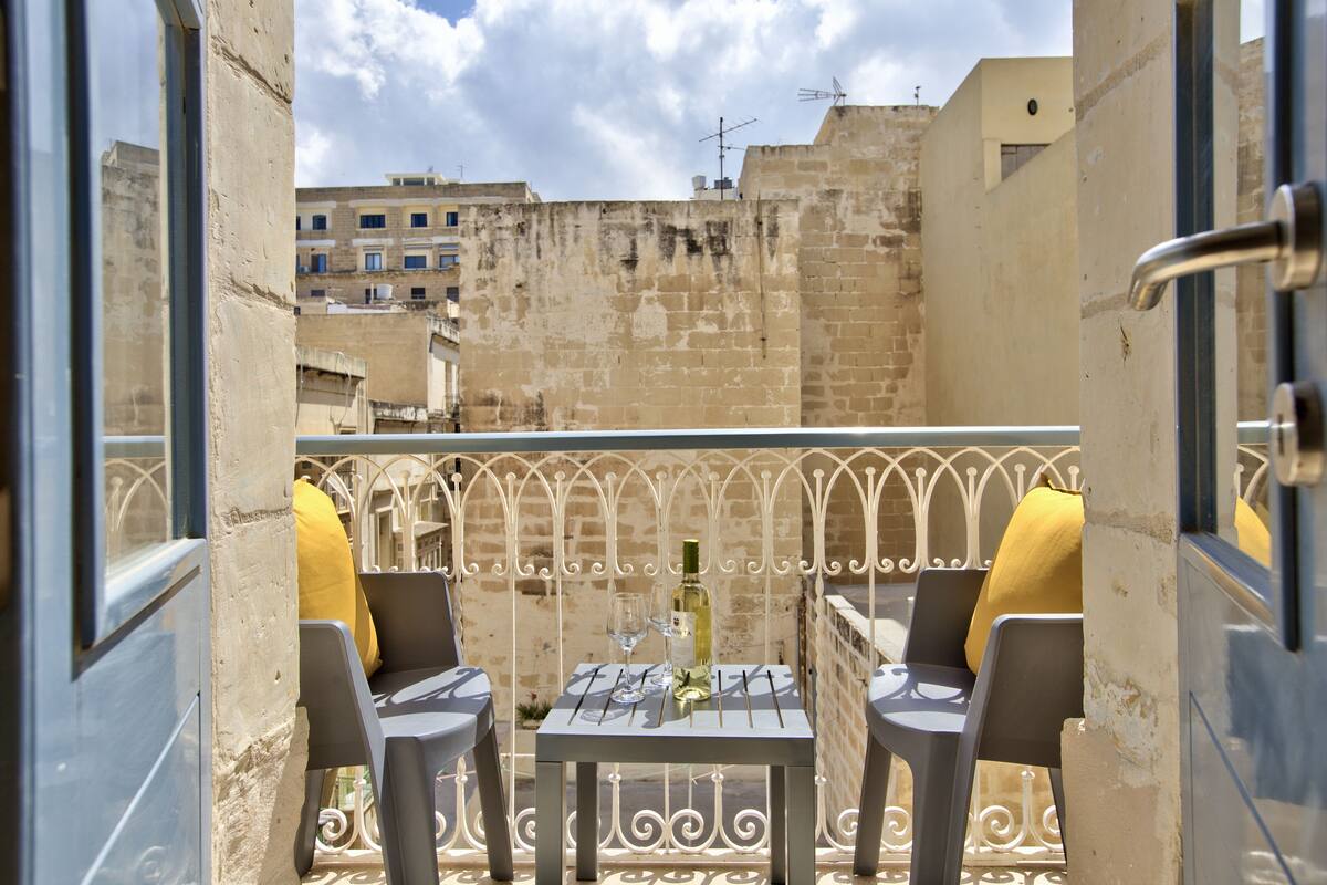 A balcony with two chairs and a table, featuring a view of the cityscape.