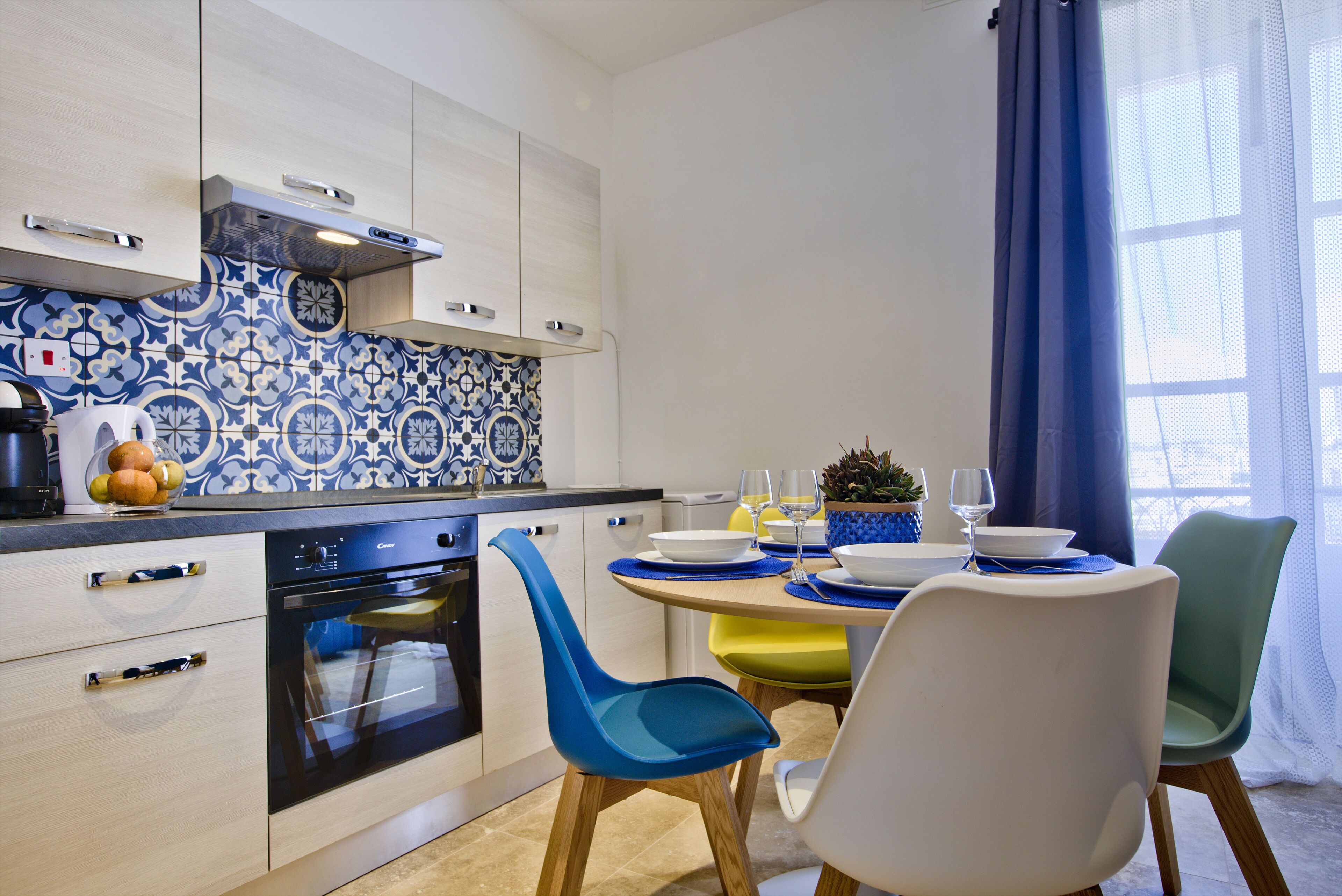 A modern kitchen with white cabinets, a built-in oven, and a blue and white patterned backsplash.