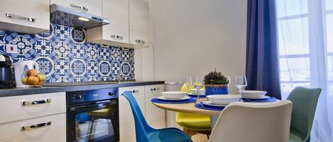 A modern kitchen with white cabinets, a built-in oven, and a blue and white patterned backsplash.