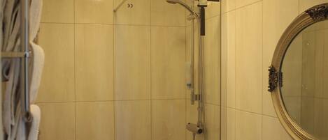 A bathroom with a toilet, sink, shower, and a mirror.
