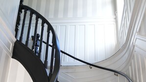 Un escalier en colimaçon avec des balustrades noires et des murs blancs.