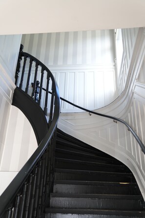 Un escalier en colimaçon avec des balustrades noires et des murs blancs.