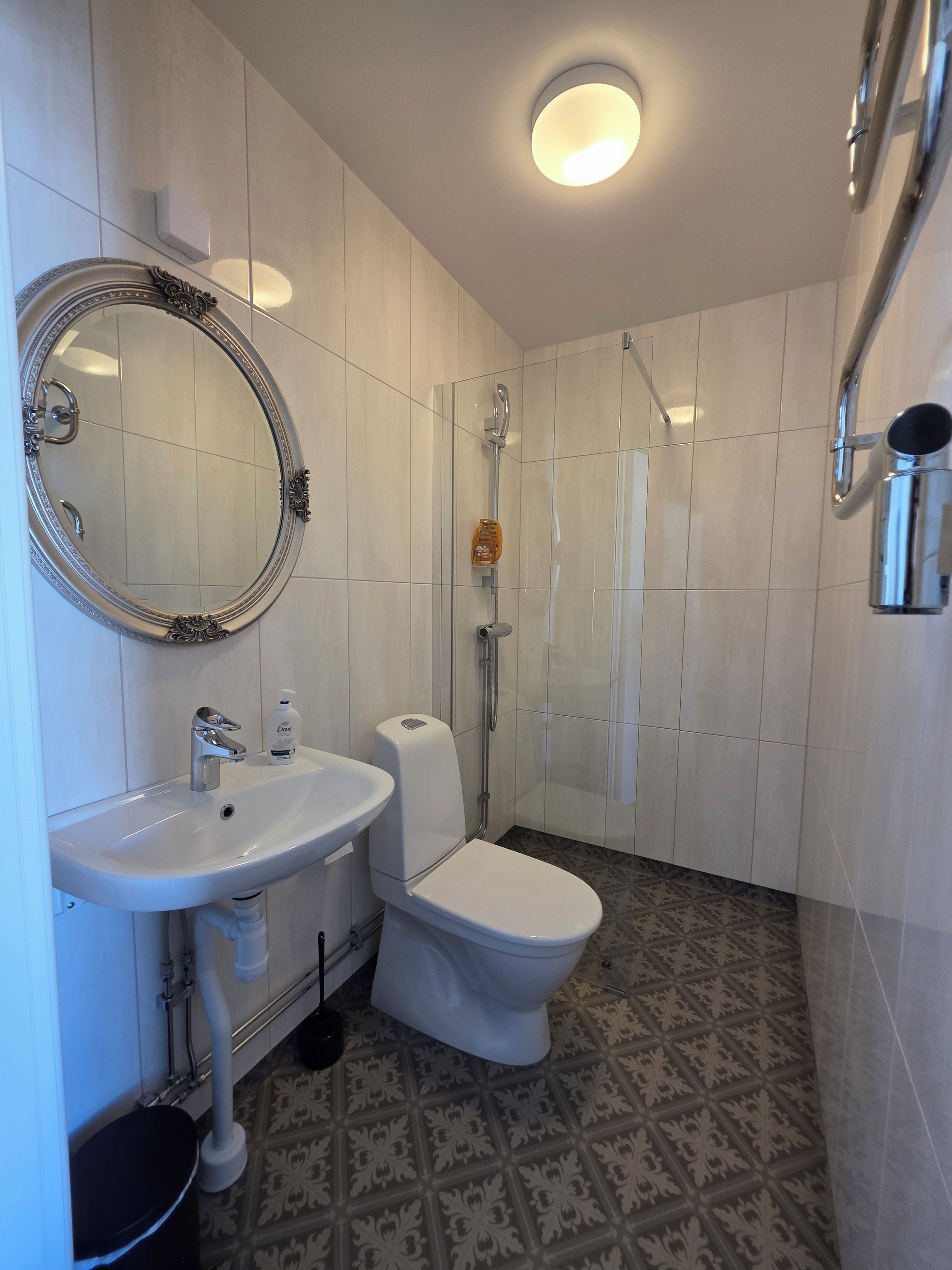 Un baño con lavamanos, inodoro y ducha blancos.