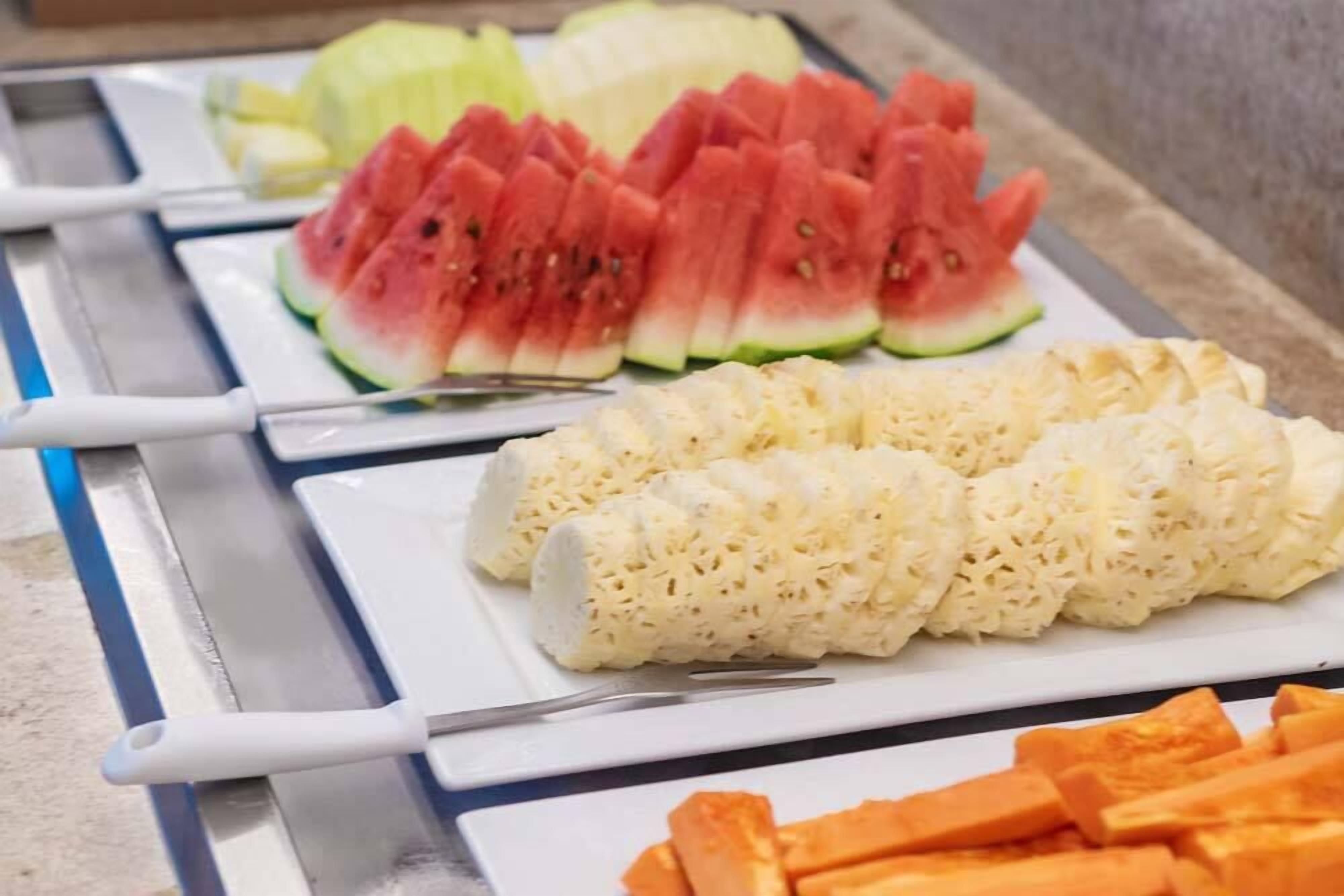 Un bufé con sandía en rodajas, queso y zanahorias.