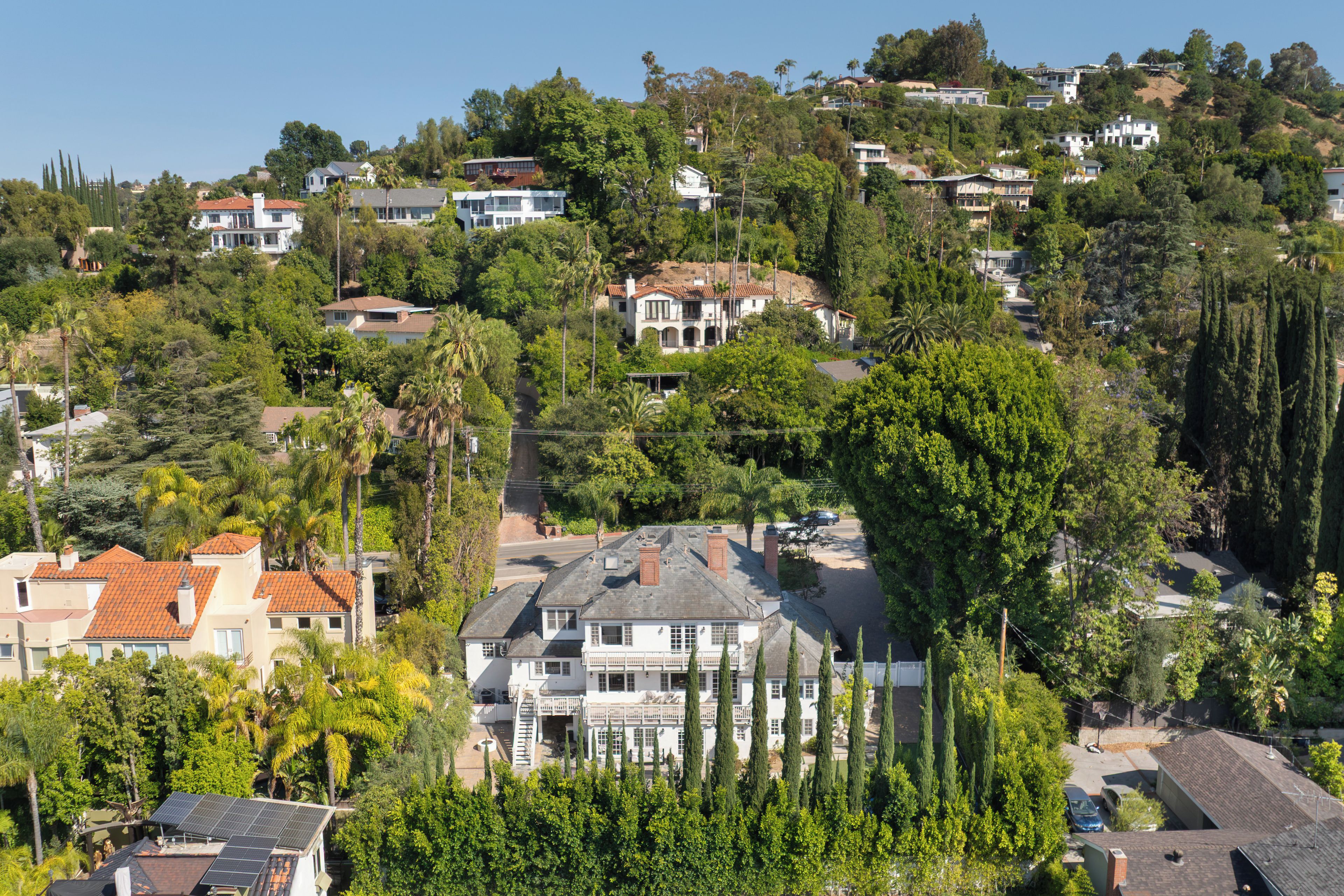 A residential area with houses surrounded by trees and hills.