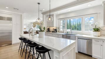 A modern kitchen with a large island, stainless steel appliances, and a view of the outdoors.