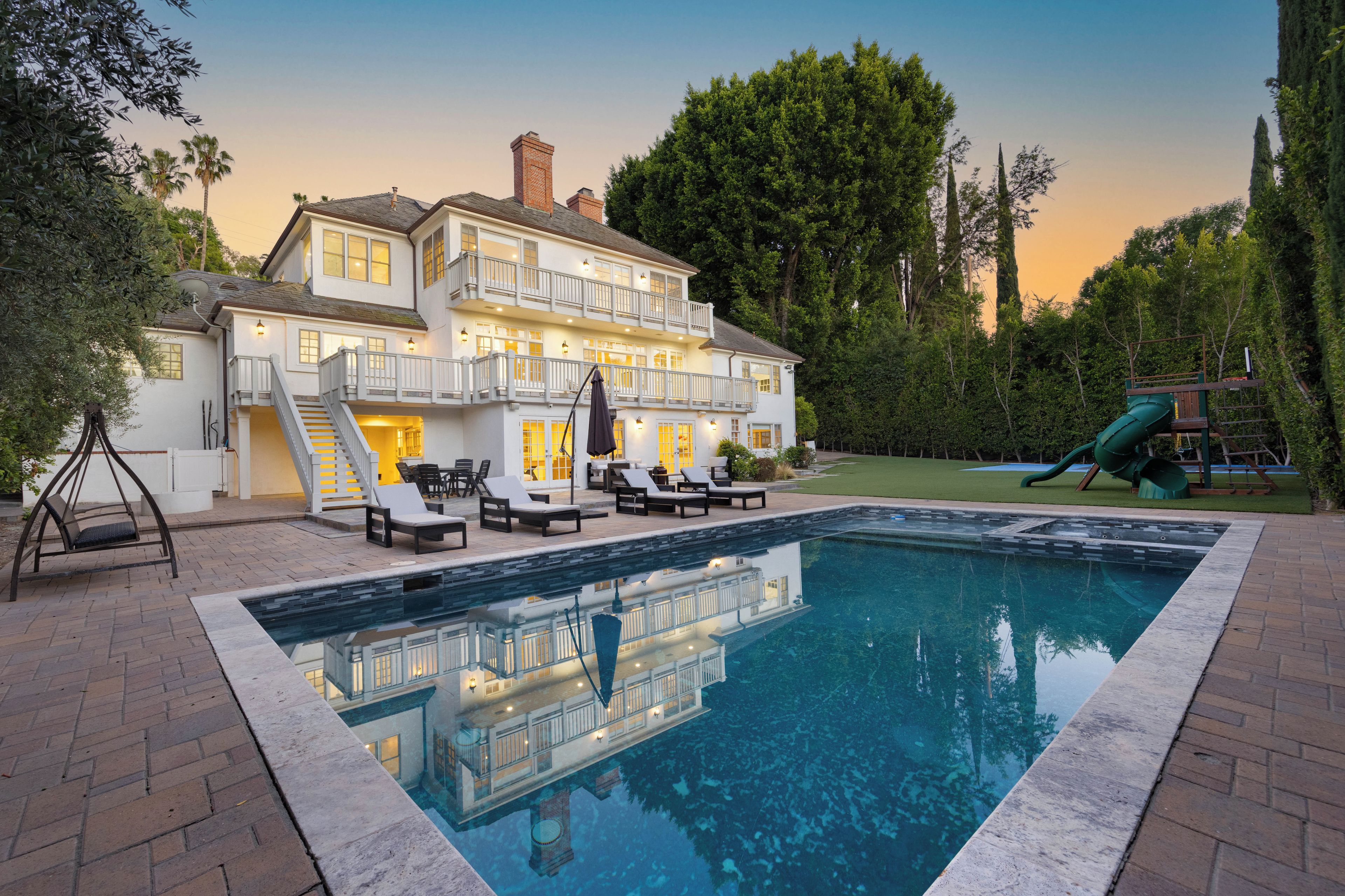 A two-story house with a swimming pool, outdoor seating, and a slide.