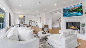 A modern living room with a fireplace, a large TV, and a cozy seating area.