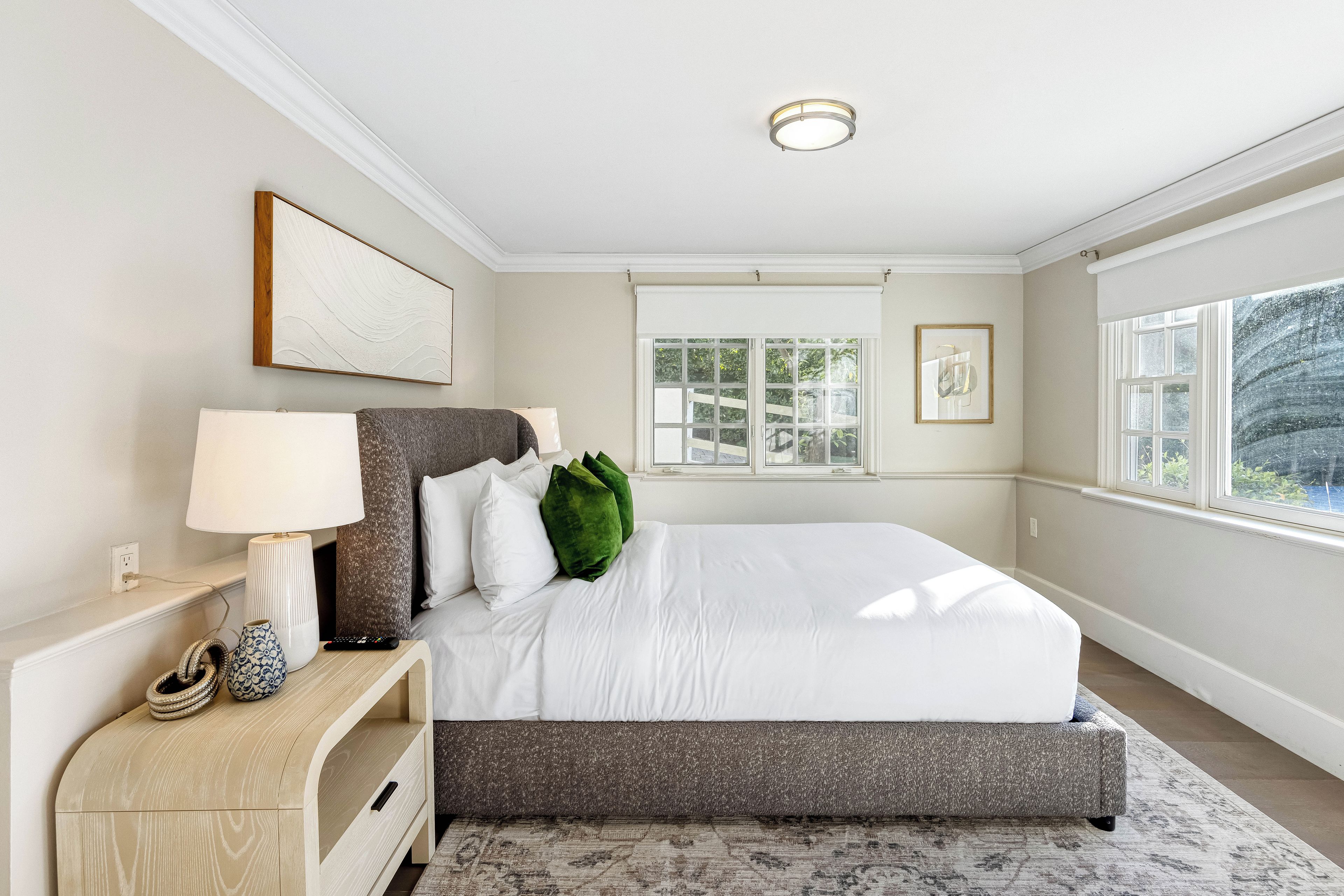 A bedroom with a bed, bedside table, lamp, and artwork on the wall.
