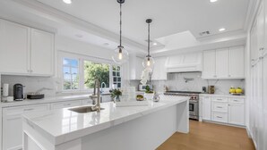 A modern kitchen with white cabinetry, a large island, and pendant lighting.