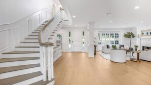 A spacious living area with a staircase, a fireplace, and a seating area.