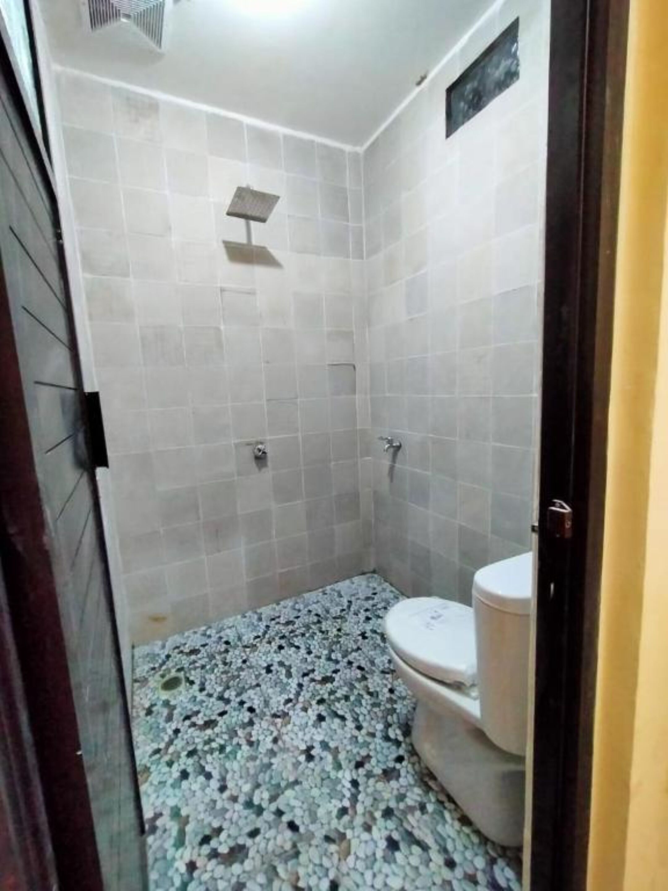 Un baño pequeño con azulejos, que incluye ducha, inodoro y suelo de cerámica.