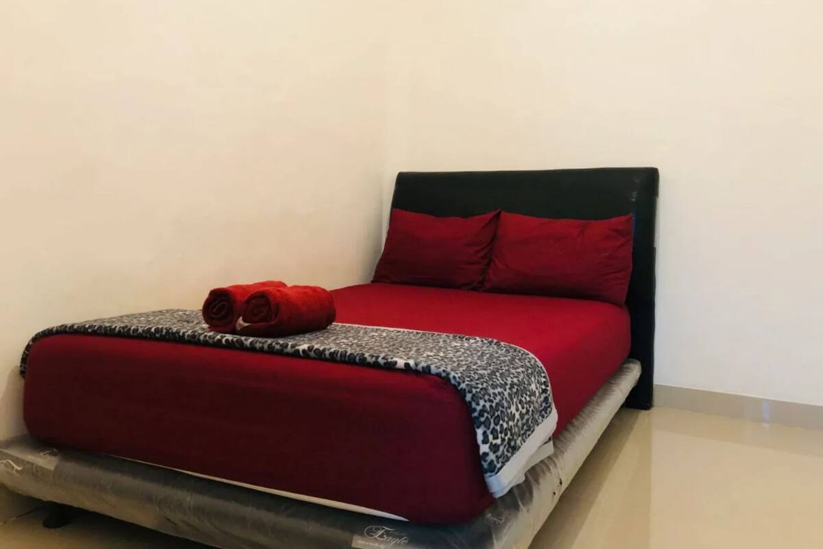 A bed with a red bedspread, two red pillows, and a leopard print blanket.