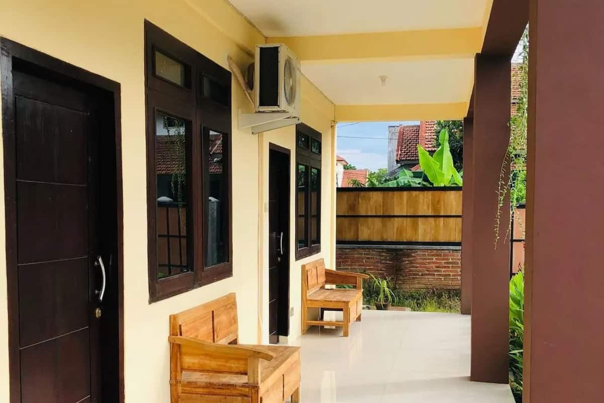 A covered outdoor area with a wooden bench, a table, and a door.
