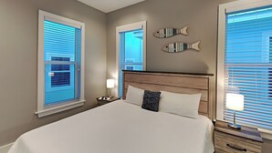 Habitación de hotel con una cama grande, dos mesitas de noche y un pez decorativo en la pared.