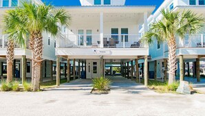 Un hotel frente a la playa con un patio central, varios balcones y palmeras.