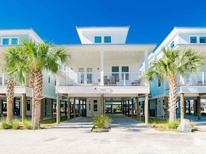 A beachfront hotel with multiple balconies, palm trees, and a covered walkway. - Fantasea | Easy Stroll to the Sand + Community Pool! (Gulf Shores)