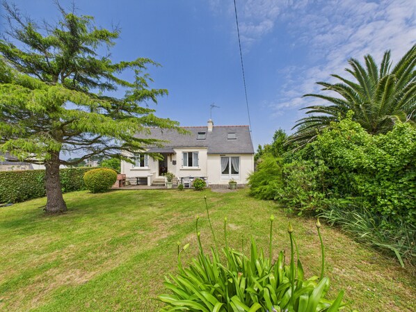 Une maison à deux étages, dotée d’un toit en pente, d’un porche à l’avant et d’une pelouse bien entretenue.