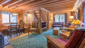 A cozy cabin interior with a wooden dining table, chairs, a sofa, and a staircase. - Summer special, stay before 9/8/26 get third night half off. (Government Camp)