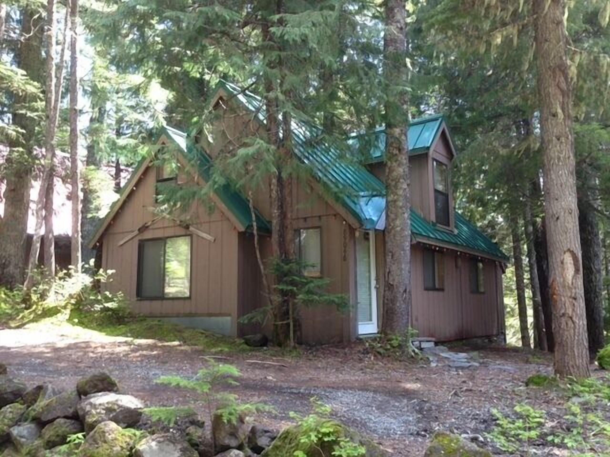 Une cabane dotée d’un toit en pente, entourée d’arbres.