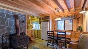 A cozy cabin interior with a stone fireplace, wooden dining table, and chairs. - Summer special, stay before 9/8/26 get third night half off. (Government Camp)