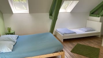 Quarto com duas camas, uma mesinha com abajur e um tapete verde.