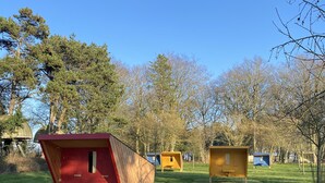 A grassy area with several wooden beehive structures. - Etretat Aventure (Les Loges)
