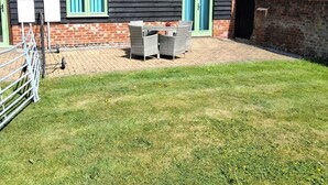 A black wooden building with a tiled roof, a green door, and a fenced patio area with outdoor furniture. - Country Views peaceful location in superb setting close to the Norfolk Broads (Loddon)