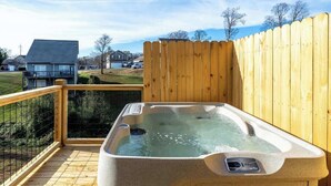 A hot tub on a wooden deck with a view of houses in the background.
