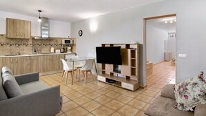 A modern living room with a sofa, TV, and dining area.
