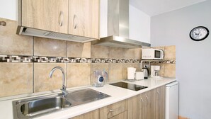 A kitchen with a stainless steel sink, wooden cabinets, a microwave, and a coffee maker.