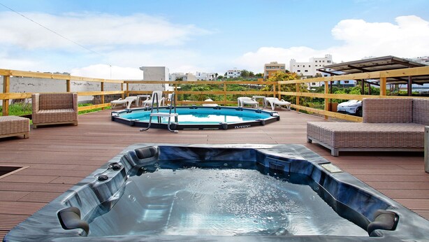 A rooftop deck with a hot tub, a swimming pool, and lounge seating.