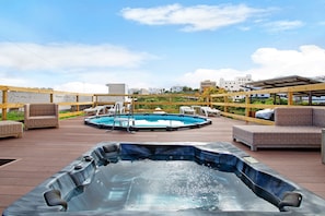 Une terrasse sur le toit équipée d’un jacuzzi, d’une piscine et de coins salon.
