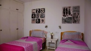 A bedroom with two beds, a wardrobe, and wall art.
