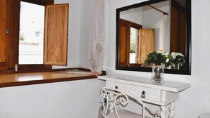 A bathroom with a wooden vanity, a large mirror, and a vase with flowers.
