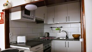 A compact kitchen with white cabinets, a microwave, a toaster, and a sink.