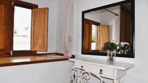 A bathroom with a wooden vanity, a large mirror, and a vase with flowers.