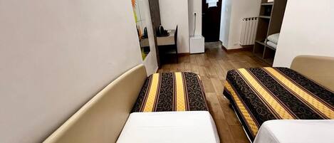 Una habitación de hotel con dos camas, un escritorio, una silla y un armario.