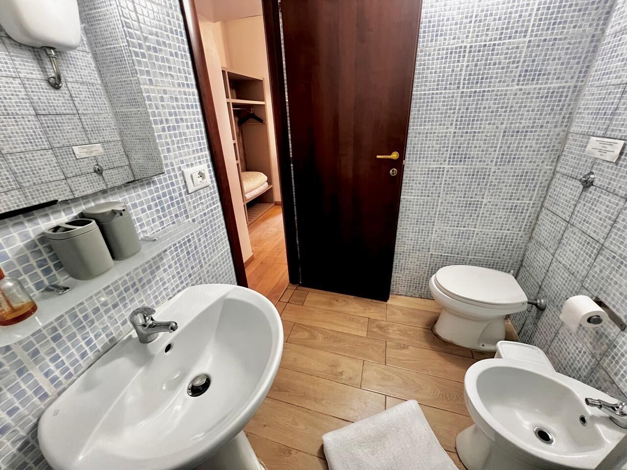Ein Badezimmer mit zwei Waschbecken, einer Toilette und einem Holzboden.