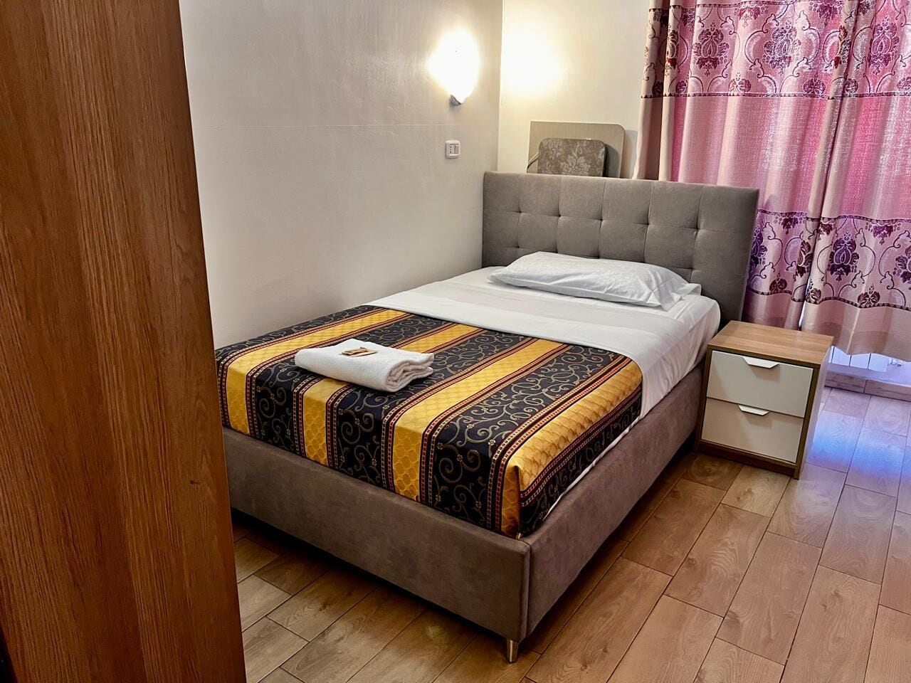 A bedroom with a bed, bedside table, and a nightstand.