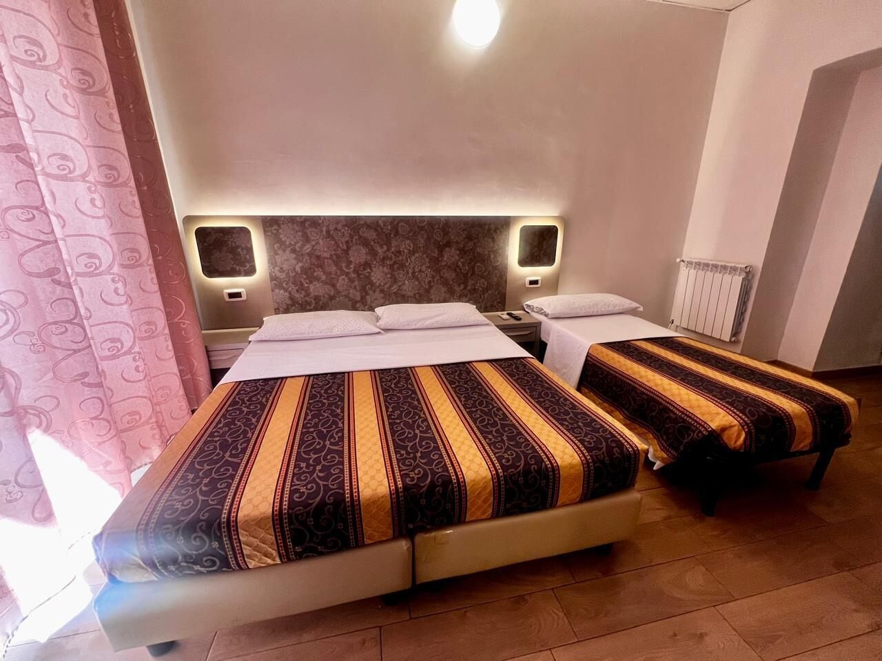 Ein Doppelbett mit einem gemusterten Überwurf, Nachttischen und einem Kopfteil.